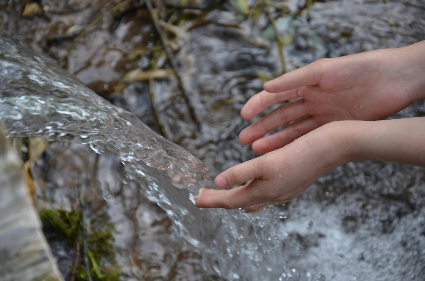 mani che toccano acqua di una sorgente